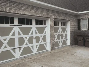 Two white garage doors with X-pattern cross-bracing on brick home exterior