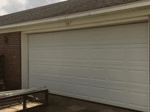 White sectional garage door with horizontal panels on brick home exterior