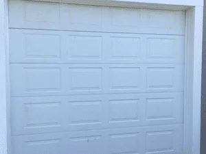 White 16-panel garage door with raised panel design, fully installed and closed