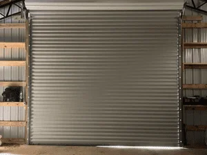 Gray aluminum sectional garage door with horizontal ribbed panels installed on residential garage